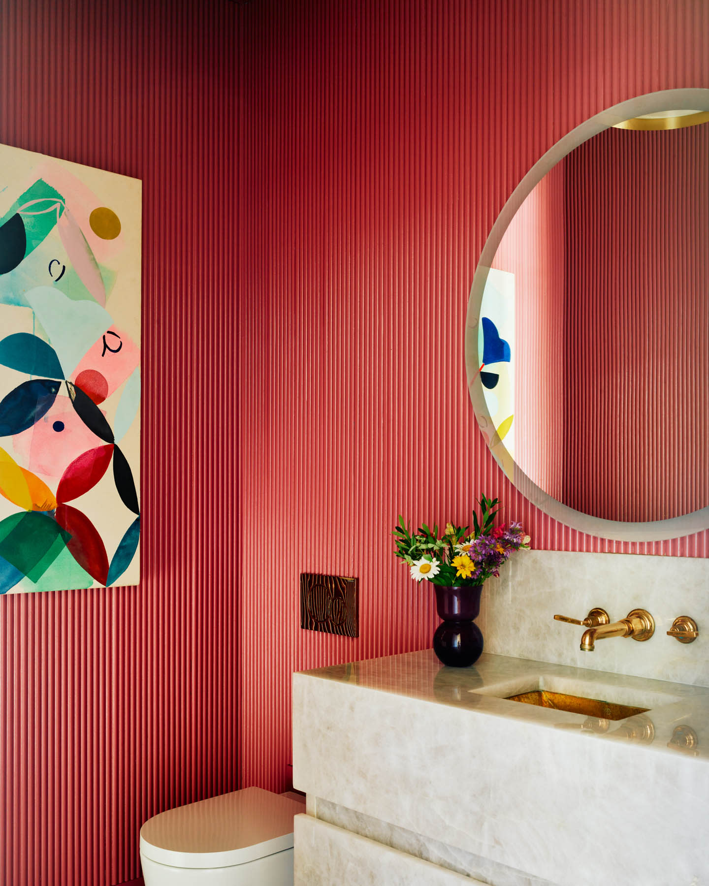 red reeded bathroom wall with a circular mirror