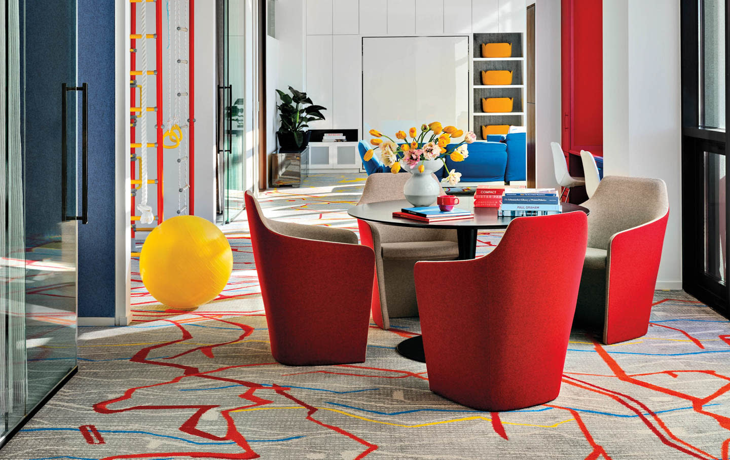 living area with bright red chairs atop a graphic grey and red carpet