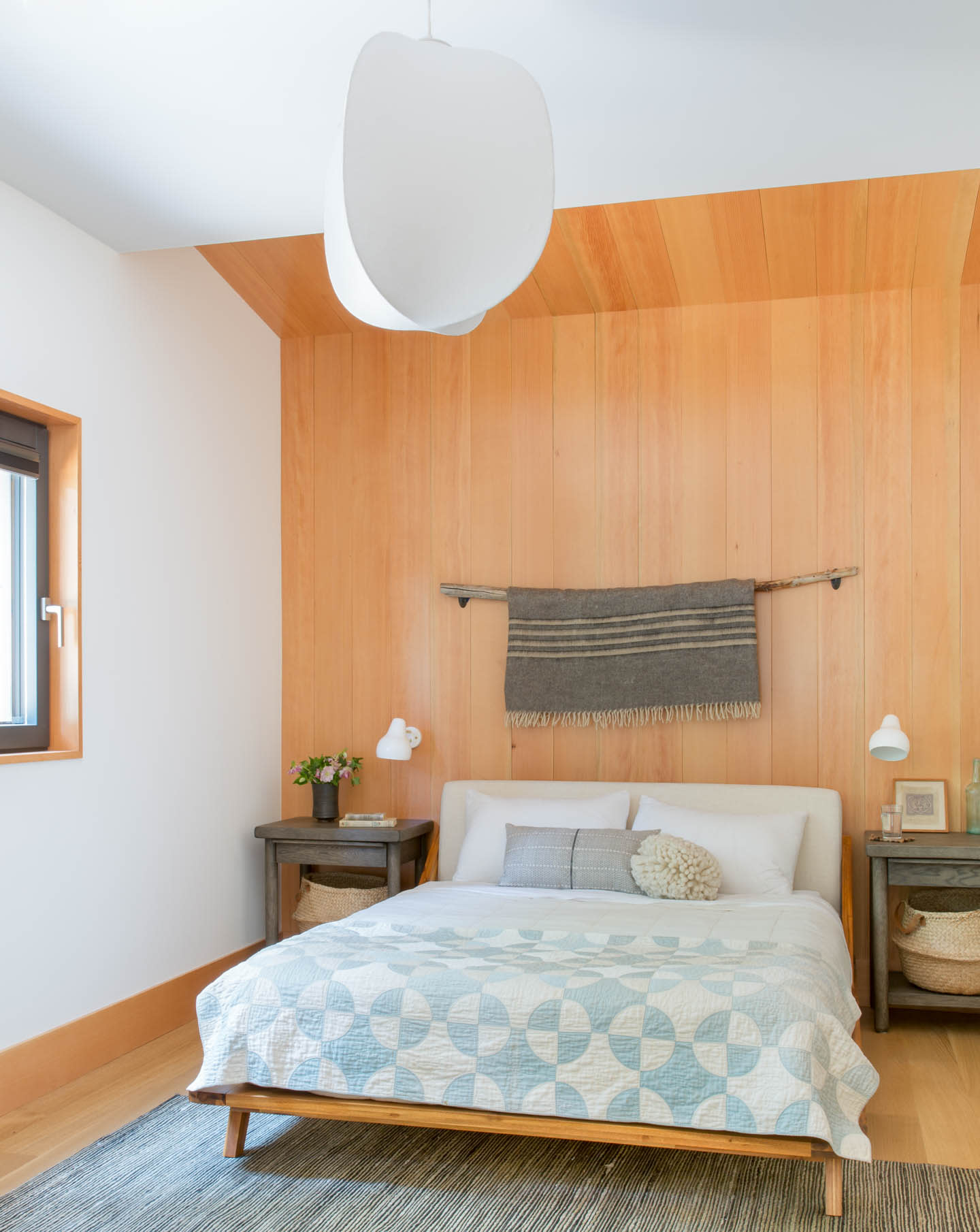 traditional bedroom with a wood accent wall behind a bed with vintage linens