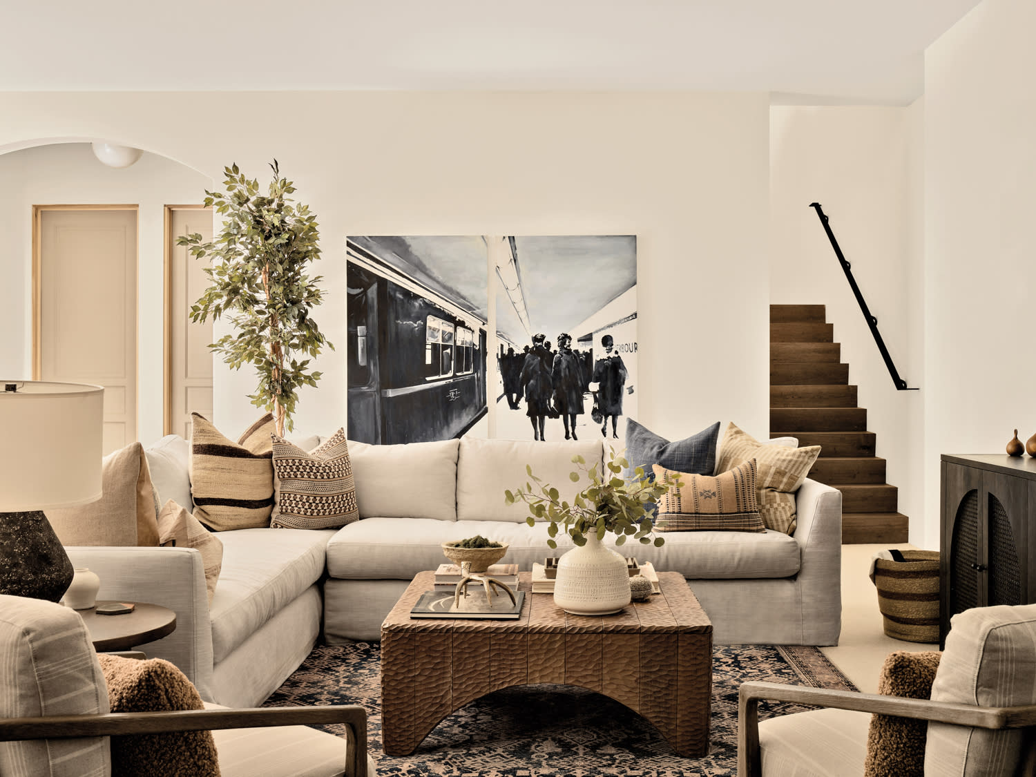 a family room with a tan sectional, textured coffee table and a black-and-white painting by Fitch Hill